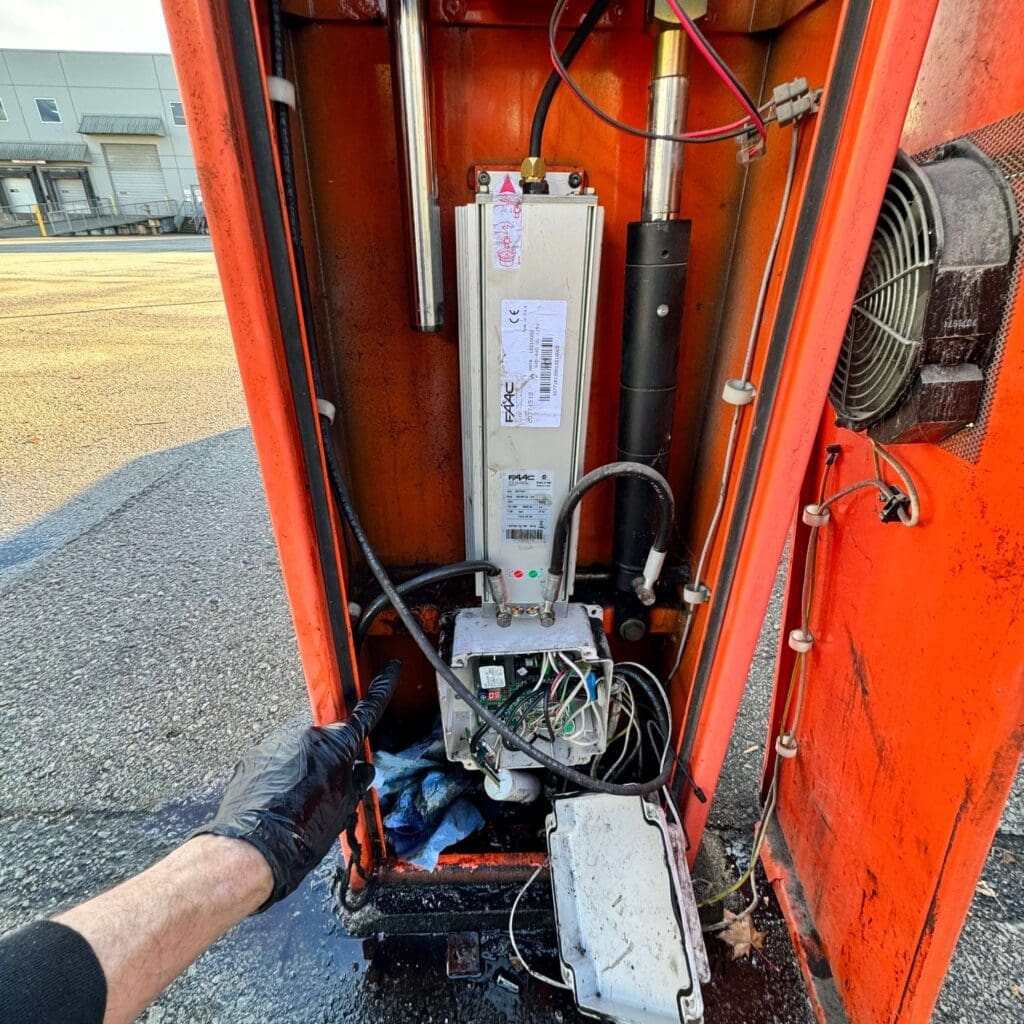 A close-up view of the internal components of a machinery cabinet, showing electrical wiring, circuitry, and hydraulic mechanisms.
