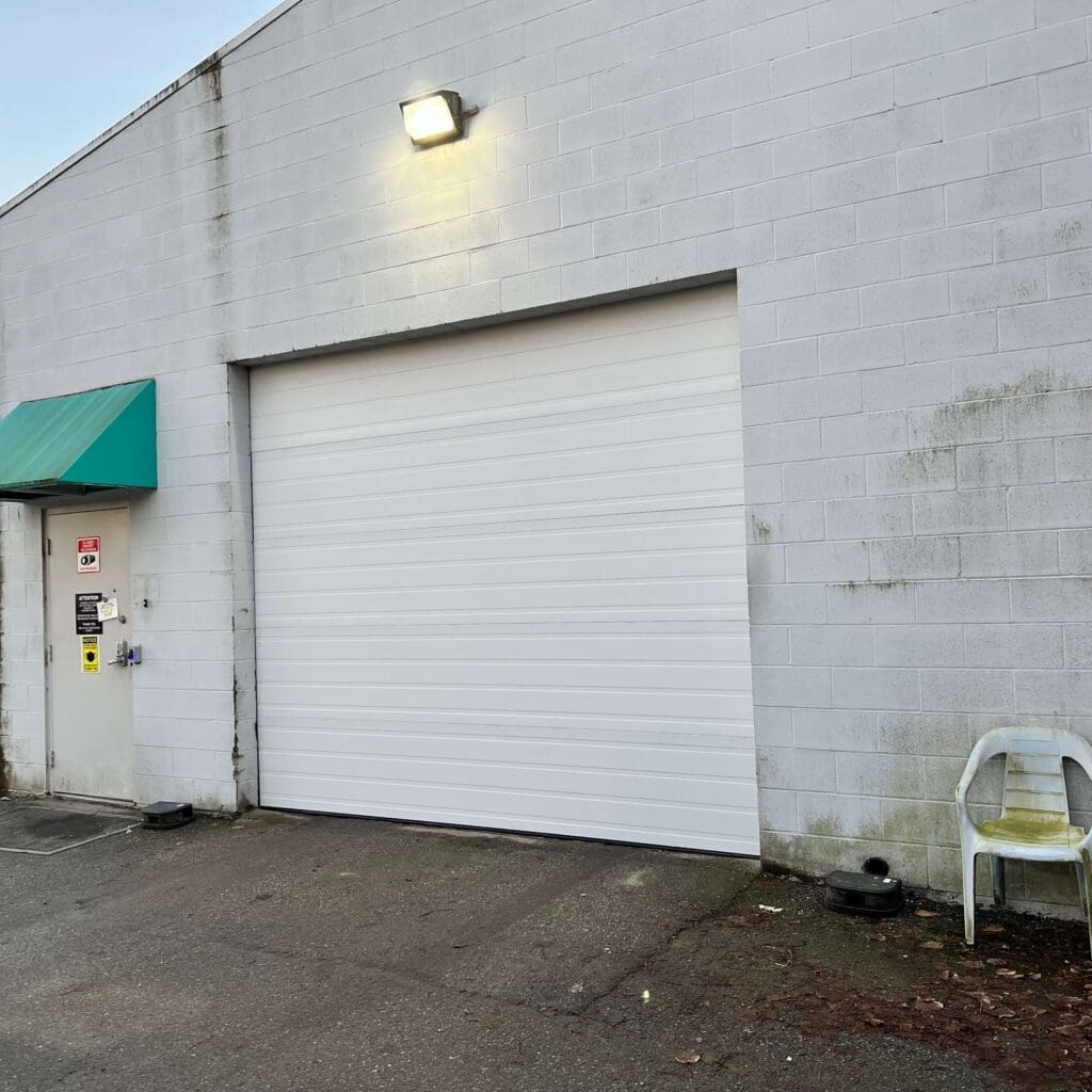 A white garage door with a red overhang, located on a concrete wall.