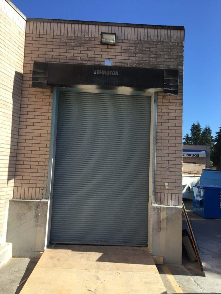 A roll-up metal door is seen on a brick building